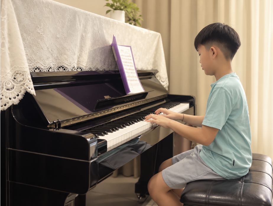 A young learner practising at an upright piano